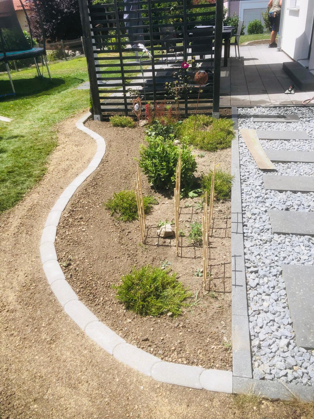 Neu angelegte Gartenfläche mit Beeteinfassung und Plattenweg