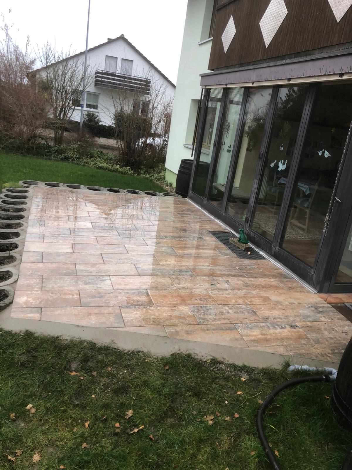 Terrasse mit warmtonigen Platten am Haus